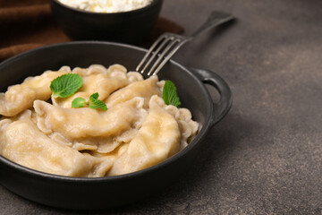 Delicious dumplings (varenyky) with cottage cheese and mint served on brown table