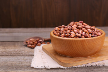 Bowl with dry kidney beans on old wooden table, closeup. Space for text