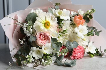 Bouquet of beautiful flowers on light grey table, closeup