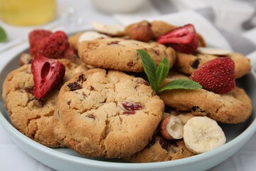 Cookies with freeze dried fruits, mint and nuts on white table, closeup