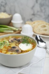 Delicious sauerkraut soup with mushrooms, dill and sour cream served on white table