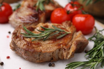 Delicious fried meat with rosemary, tomatoes and spices on white table, closeup
