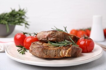 Delicious fried meat with rosemary and tomatoes on white table, closeup