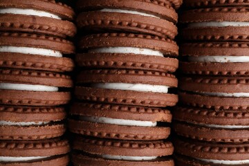 Tasty chocolate sandwich cookies with cream as background, top view