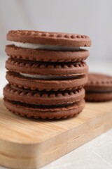 Fototapeta na wymiar Tasty chocolate sandwich cookies with cream on wooden board, closeup