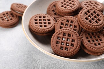Tasty chocolate sandwich cookies with cream on light grey table, closeup