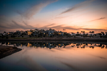 Sonnenuntergang an der Lagune bei Ancient Sands in El Gouna, &Auml;gypten. Die LAndschaft mit den Plamen und H&auml;usern spiegelt sich im Wasser.
