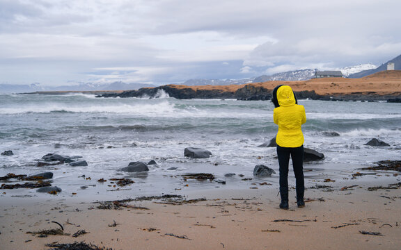 Photographer at Ytri Tunga beach in Sn&aelig;fellsj&ouml;kull National Park at Snaefellsnes Peninsula, Iceland. Coastline with black volcanic rocks and orange sea ​
