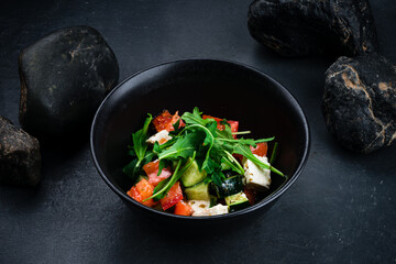 Salad of fresh cucumber, tomato, sweet pepper, arugula and feta cheese in bowl.