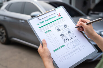 Action of a customer is signing on the agreement term of car rental service. Close-up and selective...