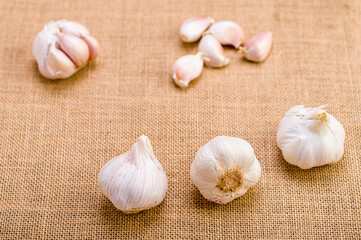 Three garlic heads in the foreground and garlic cloves out of focus in the background