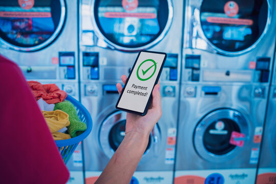 Young woman pays for laundry service using phone and banking application - Powered by Adobe