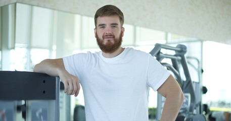 Fototapeta na wymiar Portrait of fit athletic young bearded man in gym, fitness trainer, coach.