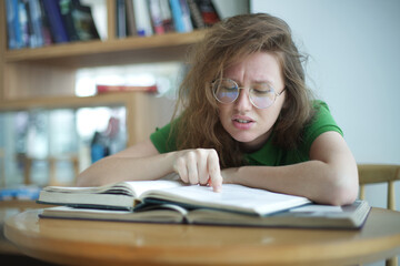 Portrait of tired overworked girl, exhausted young woman in glasses college or university student is study hard in library, prepare to exam, lesson