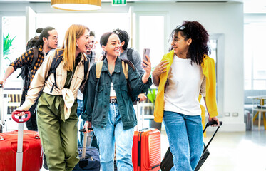 Multi racial diverse friends group arriving at hotel resort lobby with suitcases - Travel vacation life style concept with young people having fun before checkin time - Bright vivid backlight filter