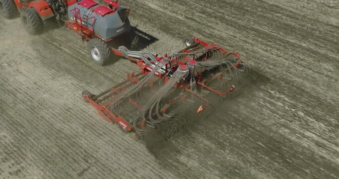 Field works. Tractor sowing seeds with seeder driller in field. Process of sowing cereals and other crops. Sowing work in the field. Tractor with seeder performing seeding. Top down drone view.