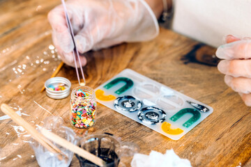 Jewelry workshop with epoxy resin. Close-up of a woman's gloved hands using jewelry tongs.