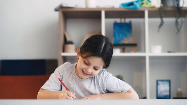 Art school. Happy little girl. Interesting hobby. Smiling female kid enjoying drawing in light studio interior.