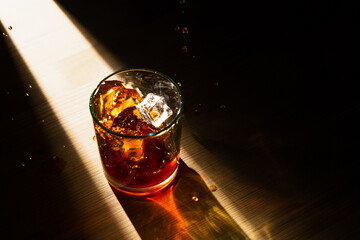 Dramatic top view of ice cubes falling in a glass of whiskey