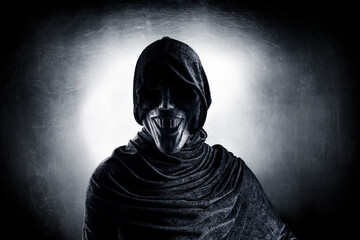 Fototapeta na wymiar Scary figure with hooded cloak in the dark