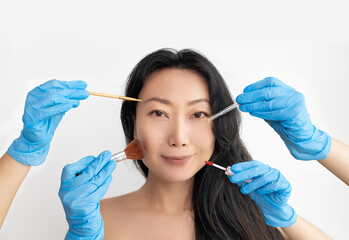 Closeup portrait of beautiful young Asian woman with makeup brushes. Red lips. Isolated over white background.