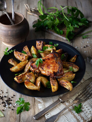 Baked potatoes with chicken meat on a black plate