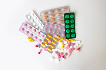 Pile of various pills on a colored background. pharmaceutical drugs antibiotics tablets medicine on white background.