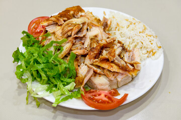 Turkish and Arabic Traditional Ramadan doner kebab with tasty tomato sauce and rice or turkish pilav in white plate on wood table background. ( Pilav ustu doner)