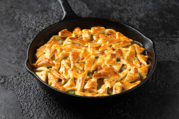 Chicken pot pie with bacon and puff pastry served in cast iron pan. Comfort food concept.