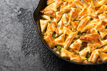 Chicken pot pie with bacon and puff pastry served in cast iron pan. Comfort food concept.