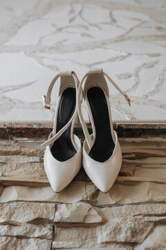 White elegant shoes. A pair of classic white shoes standing on a windowsill on a stone background. Fashion. Style. Wedding photo