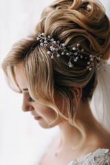 Naklejka premium Wedding details. Photo of an elegant hairstyle of a blonde bride. Beautiful curls. Beautiful hair and makeup. Diadem
