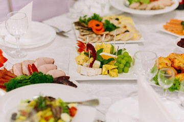 buffet table at the wedding. Cheese plate. Assortment of canapés. Banquet service. food, snacks with cheese, ham, prosciutto and fruit.