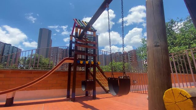 Lonely Swing in Medellin's Urban Playground, during midday and sunny blue sky and clouds
