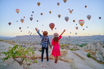 Traveling couple with open arms standing together in magical valley in Anatolia, Kapadokya. Flying...