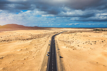 Fuerteventura, Corralejo sand dunes nature park. Beautiful Aerial Shot. Canary Islands, Spain. Aerial view of an empty road through the dunes at the sunset. Fuerteventura, Canary Islands, Spain.