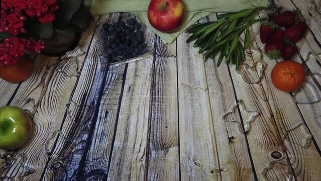 cookie cutters forming on the wooden surface surrounded by fruits. High quality 4k footage