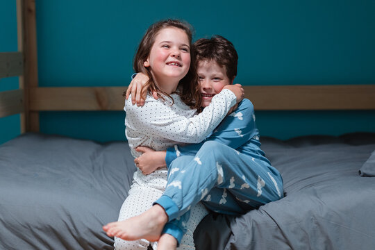 Happy kids sitting on bed and embraced