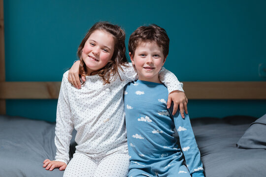 Happy kids sitting on bed with hands on shoulders