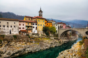Obraz premium Beautiful ancient mediterranean town with stone arch bridge and emerald river. Kanal town in Slovenia. Small town of Kanal, Slovenia with the clear turquoise Soca River carving the white rocks.