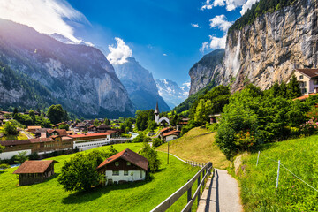 Amazing summer landscape of touristic alpine village Lauterbrunnen with famous church and Staubbach...