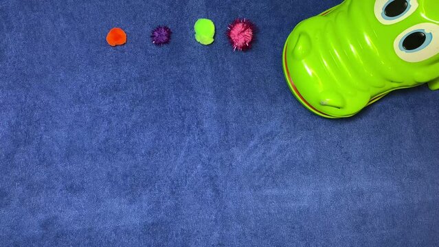 Craft ideas, intro stop motion. Pom pomps around the crocodile on the blue surface. High quality 4k footage