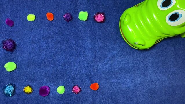 Craft ideas, intro stop motion. Pom pomps around the crocodile on the blue surface. High quality 4k footage