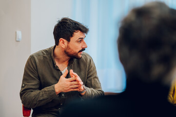 Young man psychologist on a group therapy session discussing mental health issues