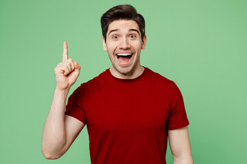 Young insighted smart proactive man he wears red t-shirt casual clothes holding index finger up with great new idea isolated on plain pastel light green background studio portrait. Lifestyle concept.