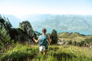 Sporty woman enjoys panorama from hike trail on lake Walensee in the morning. Schnürliweg,...