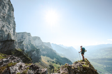 A sporty woman enjoys the  amazing view from a vantage point on churfürsten mountain range in the morning. Schnürliweg, Walensee, St. Gallen, Switzerland, Europe.