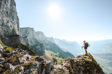 A young sporty woman enjoys the  amazing view from a vantage point on churfürsten mountain range in the morning. Schnürliweg, Walensee, St. Gallen, Switzerland, Europe.