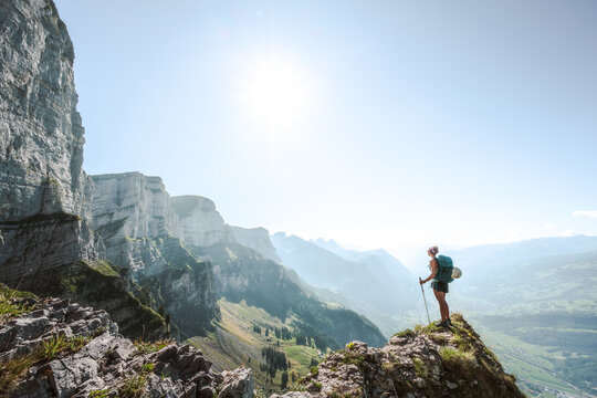 A sporty woman enjoys the  amazing view from a vantage point on churf&uuml;rsten mountain range in the morning. Schn&uuml;rliweg, Walensee, St. Gallen, Switzerland, Europe.