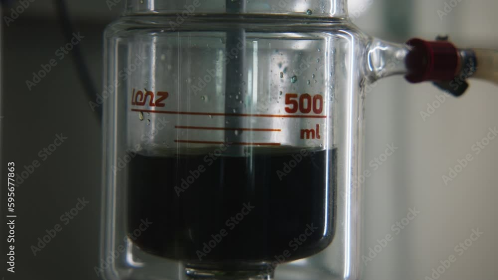 Poster rotating dark liquid in laboratory flask. stock footage. bubbling liquid in flask with installation 